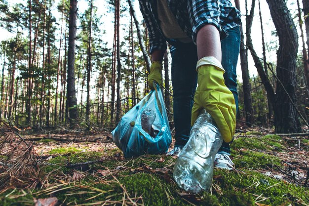 Photo a woman with a garbage bag collects plastic garbage in the autumn forest saving the planet from