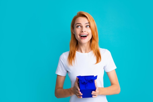 Woman with gift Portrait of excited young girl holding gift box isolated blue background Pretty girl with present