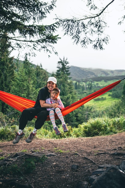 woman with girl kid on hammock mountains on background hiking concept