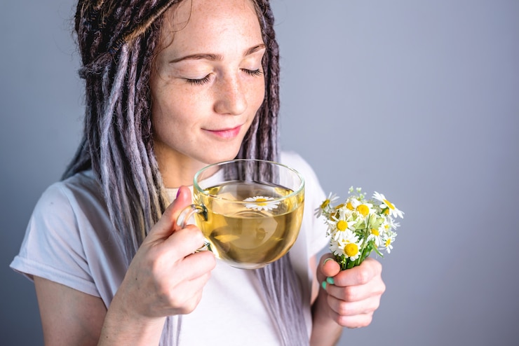 Woman with a glass cup of hot chamomile tea
