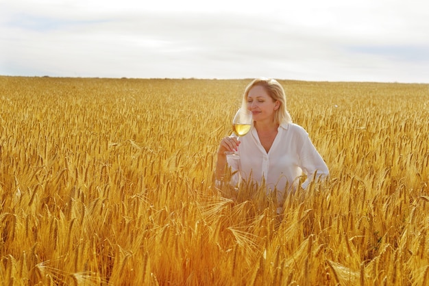 Woman  with glass of wine in wheat field