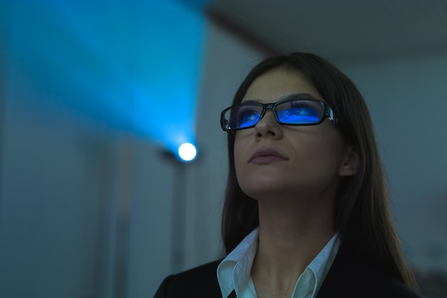 The woman with glasses against the background of the projector