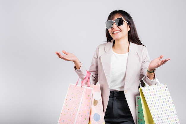 Woman with glasses confident shopper smiling holding online shopping bags colorful multicolor