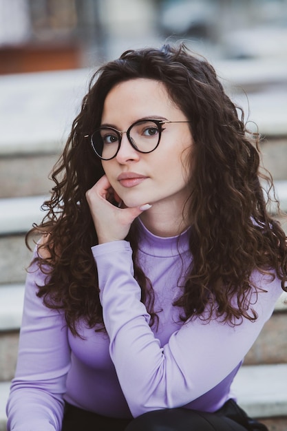A woman with glasses on and a purple top