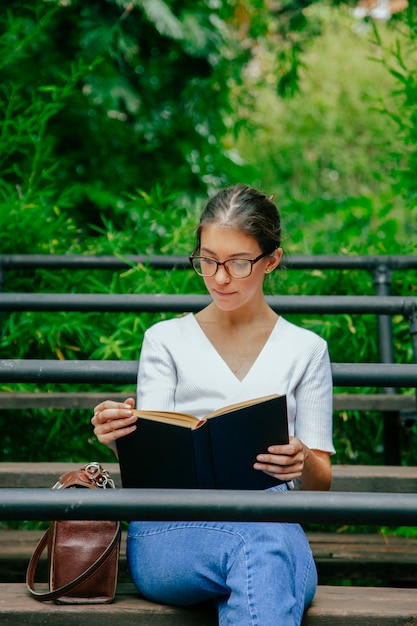 Woman with glasses reading a book outside