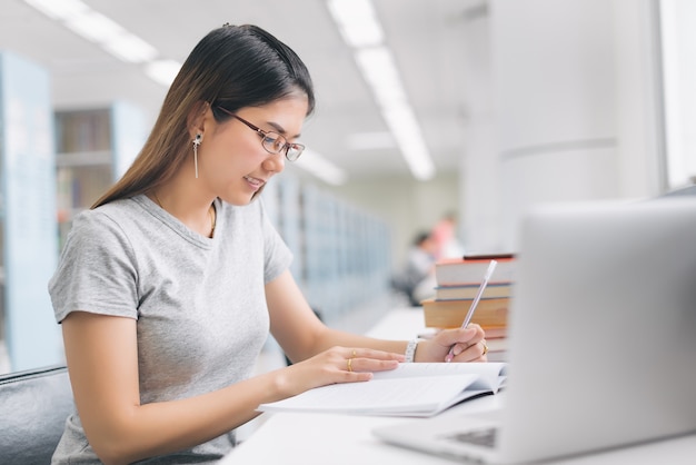 Woman with glasses taking a note and working with laptop.