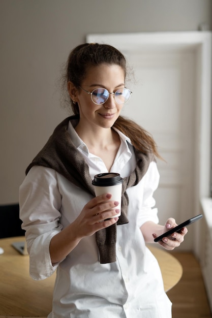 A woman with glasses uses the phone a freelancer works in an office