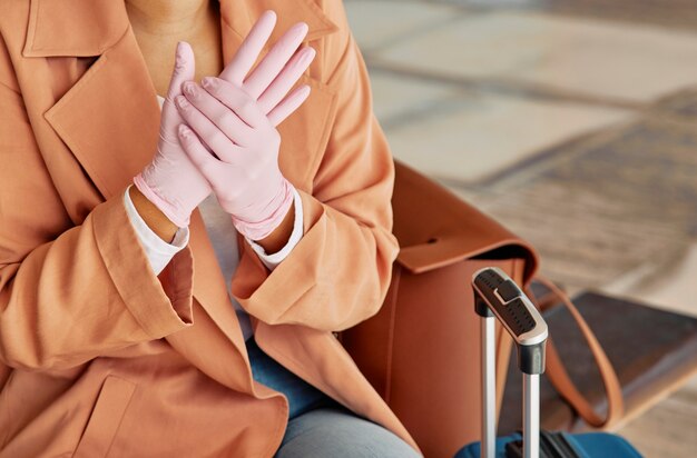 Foto donna con guanti e bagagli in aeroporto durante la pandemia