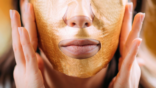 Foto donna con la maschera di bellezza del fronte dell'oro