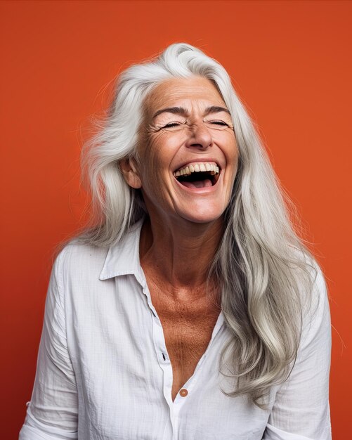 Foto una donna con i capelli grigi che ride di fronte a uno sfondo arancione