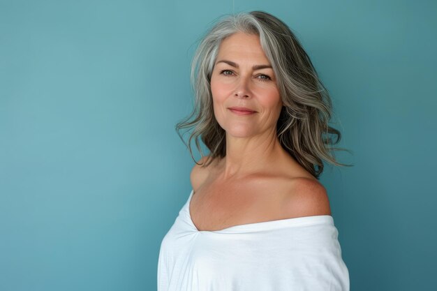 A woman with gray hair posing against a blue background