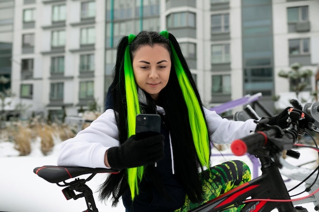 Foto donna con i capelli verdi e neri in piedi accanto alla bicicletta