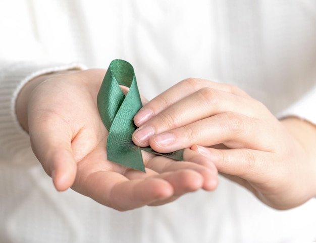 Foto una donna con il nastro verde assistenza sanitaria e concetto della giornata mondiale del cancro