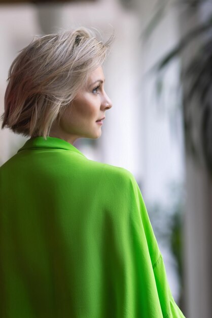 A woman with a green shawl looks out a window.