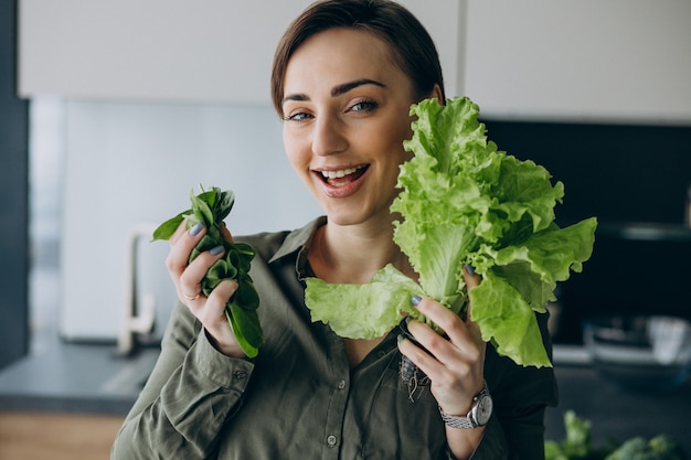 台所で緑の野菜を持つ女性