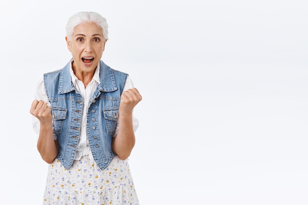 woman with grey hair, clench hands, fist pump celebrating win, won lottery, say yes cheerfully, achieve success