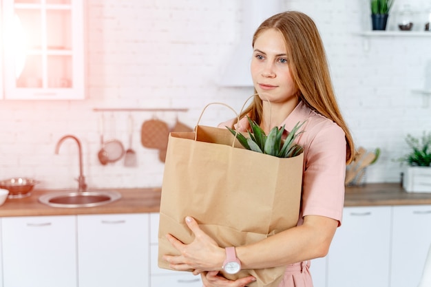 手に食料品店のパケットを持つ女性。