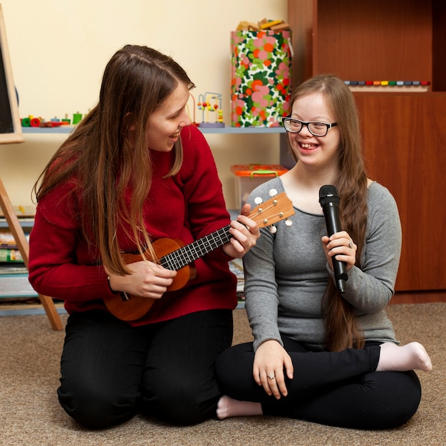 woman with guitar and girl with down syndrome having fun