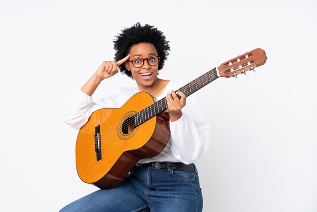 Donna con una chitarra sul muro bianco