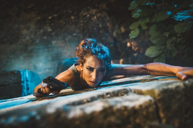 Foto donna con una pistola che si arrampica sul muro