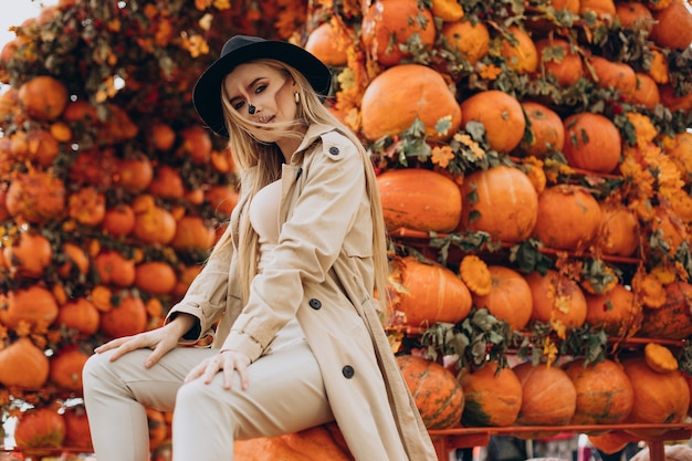 Photo woman with halloween make up standing by halloween pumpkins