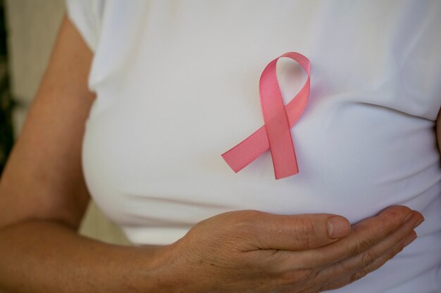 Photo woman with hand on breast and pink bow on tshirt breast cancer prevention campaign pink october