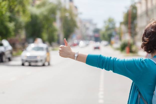 Donna con la borsa che ferma un taxi che cammina in via della città