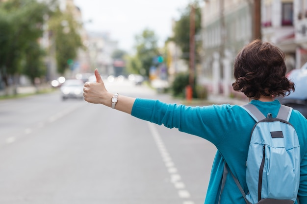 Donna con la borsa che ferma un taxi che cammina in via della città