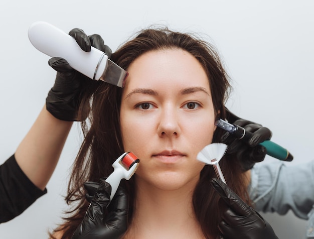 Женщина с руками нескольких терапевтов с косметологическими приборами возле лица женщина нуждается в уходе за кожей концепция ухода за кожей фото