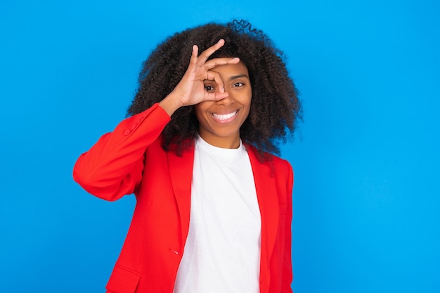 woman with happy face smiling doing ok sign with hand on eye looking through finger