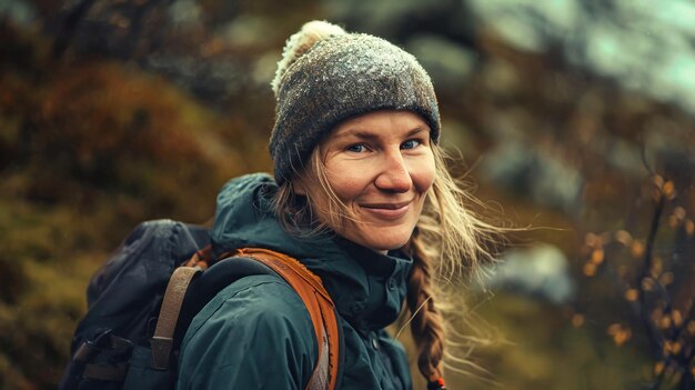 A woman with a hat and backpack hiking in the mountains