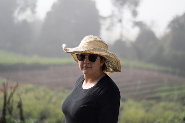 woman with hat and glasses with nature background in sunny and foggy day