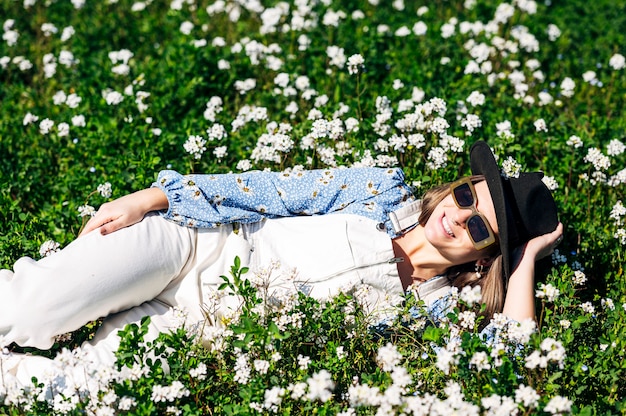 Woman with hat lying in flower field