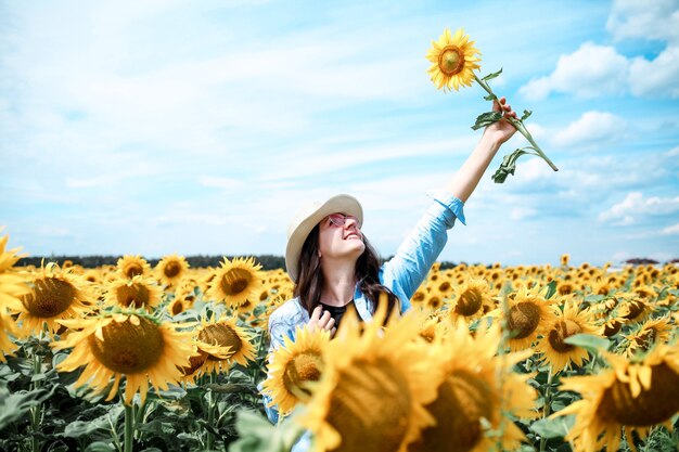Woman with hat in sunflowers field enjoying nature