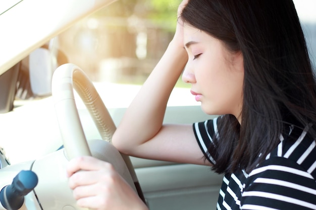 woman with head in hands while driving car