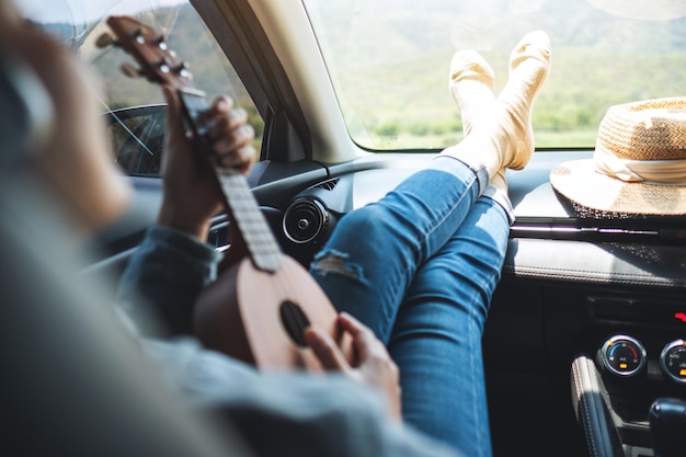 A woman with headphone playing Ukulele while riding in the car