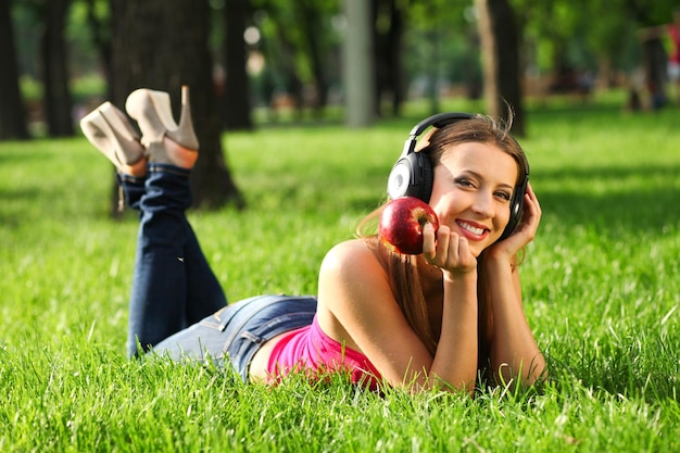 Woman with headphones listening music on the grass