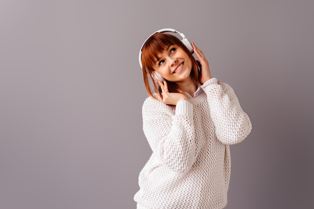 Woman with headphones listening music isolated on grey background