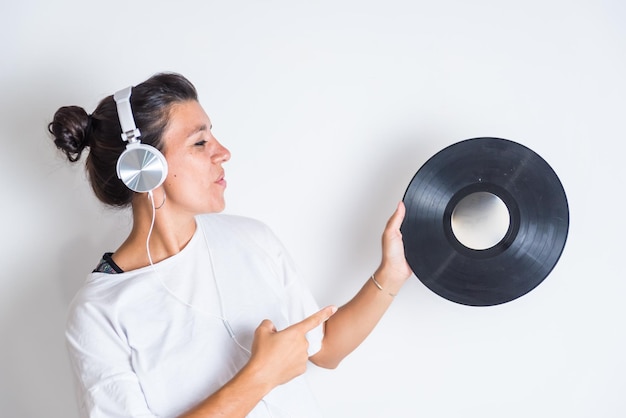 A woman with headphones points to a vinyl record music