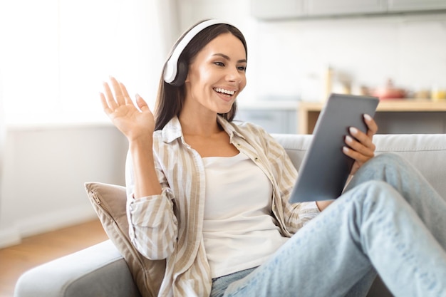 家でタブレットを使っているヘッドフォンをかけた女性