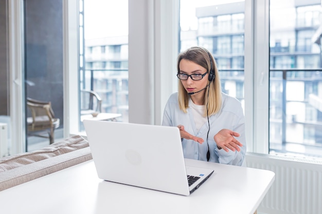 woman with a headset and glasses communicates with customers at a distance  of a laptop