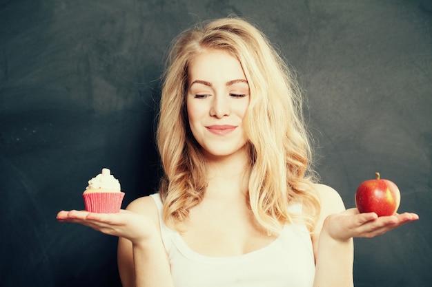 健康的な食べ物と不健康な食べ物を持つ女性。難しい選択。太りすぎの概念