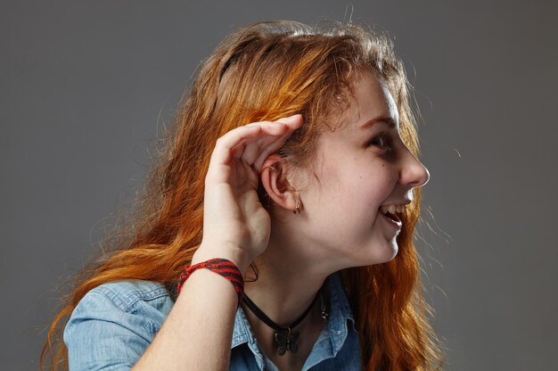 Woman with a hearing disorder or hearing loss cupping her hand behind her