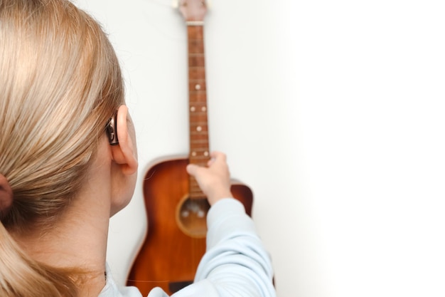 Foto una donna con perdita dell'udito può sentire e suonare di nuovo la chitarra usando un apparecchio acustico una donna adulta con un apparecchino acustico dietro l'orecchio può sentire i suoni