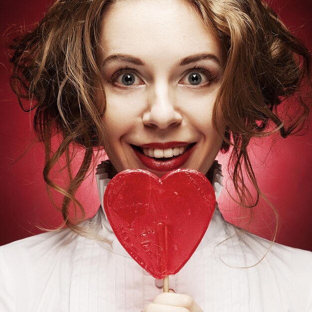 Foto donna con caramello cuore su sfondo rosso