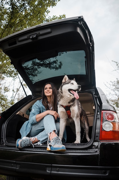 Photo woman with her adorable husky traveling by car