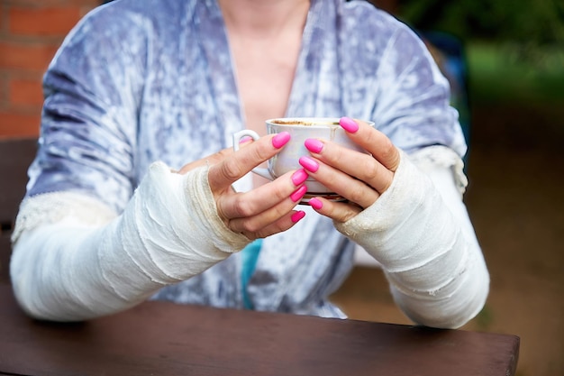 A woman with her arms crossed holds a cup of coffee in her hands