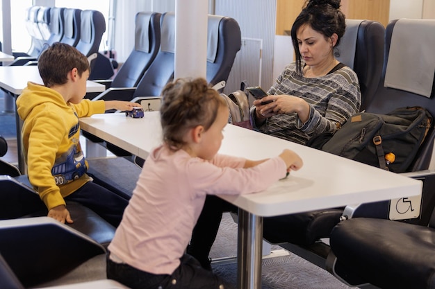 Женщина с детьми, путешествующая на пароме, сидит и смотрит мобильный телефон
