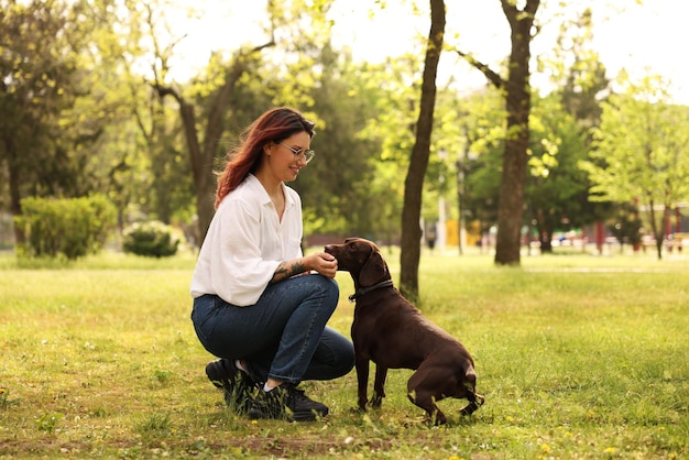 春の日に公園で可愛いドイツのショートヘアポインター犬を飼っている女性