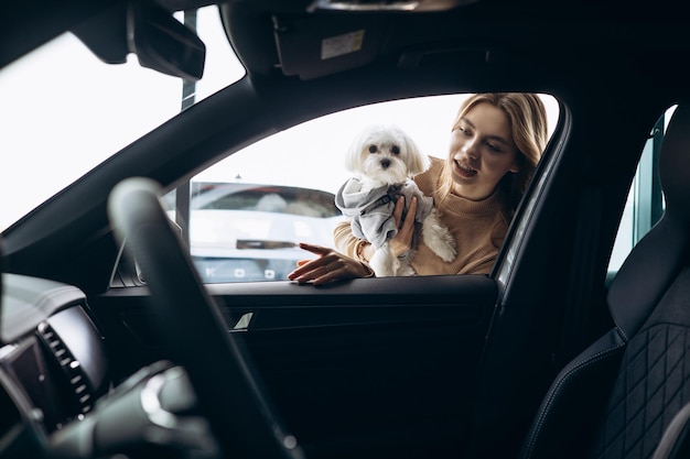 Photo woman with her dog by the car in a car showroom